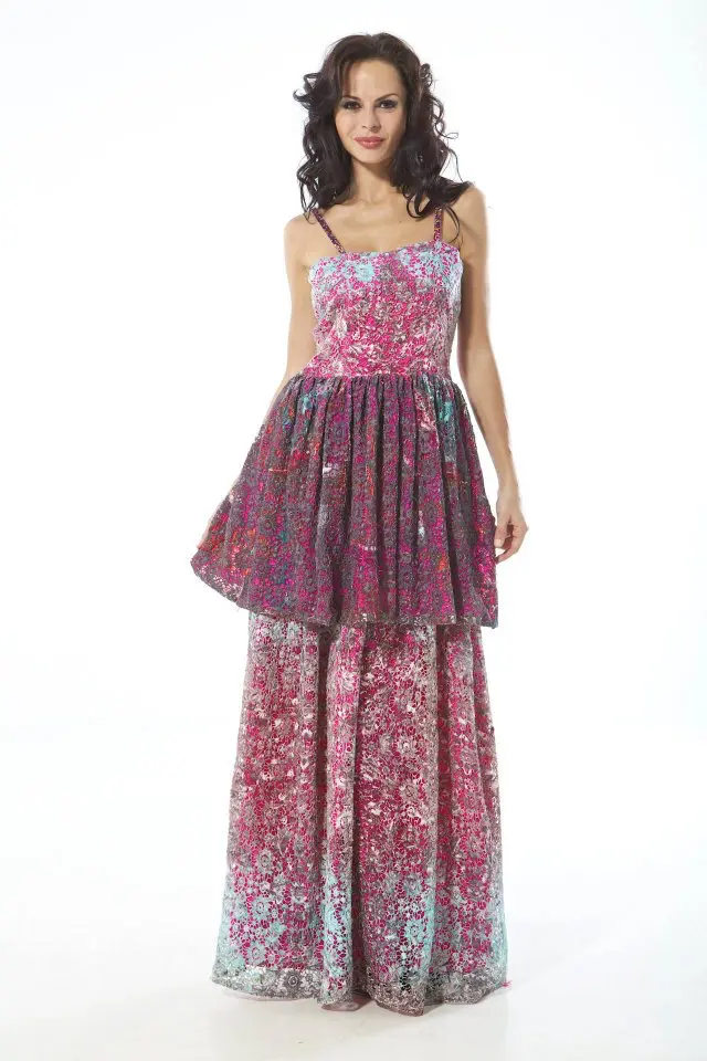 Model wearing a long corseted dress with Swarovski-strapped shoulders, printed in reds and blacks over net with a sky blue lining for contrast.